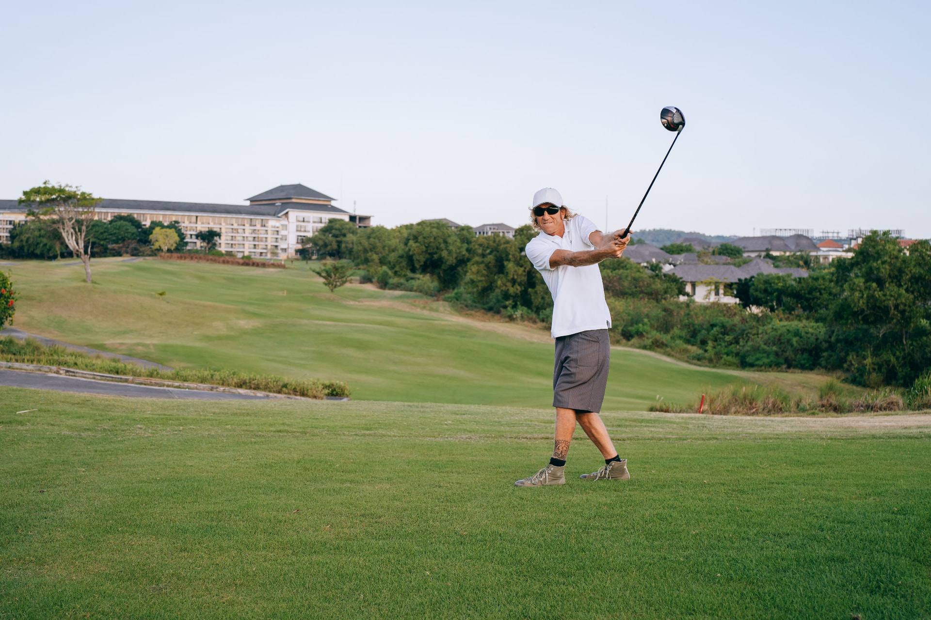 Golf resort digital marketing: golfer teeing off on a destination golf course in front of the resort hotel